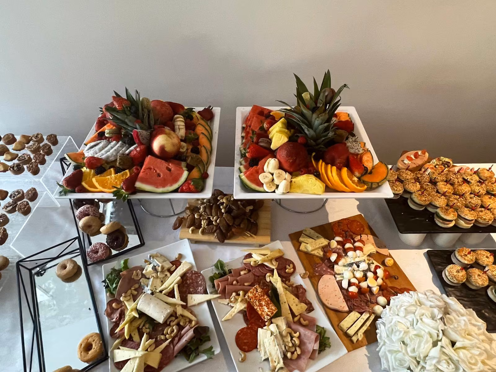 Buffet avec plateaux de fruits et ananas, fromages, charcuterie et donuts