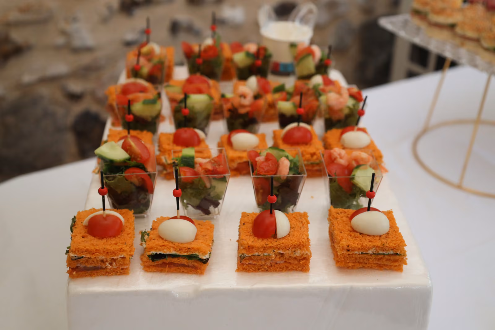 Canapés à la tomate et à l'œuf de caille, verrines de légumes et brochettes sur un buffet blanc