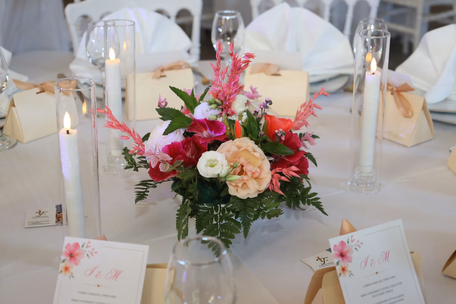 Centre de table de mariage : bouquet rose et fuchsia, bougies, boîtes à dragées et menus imprimés