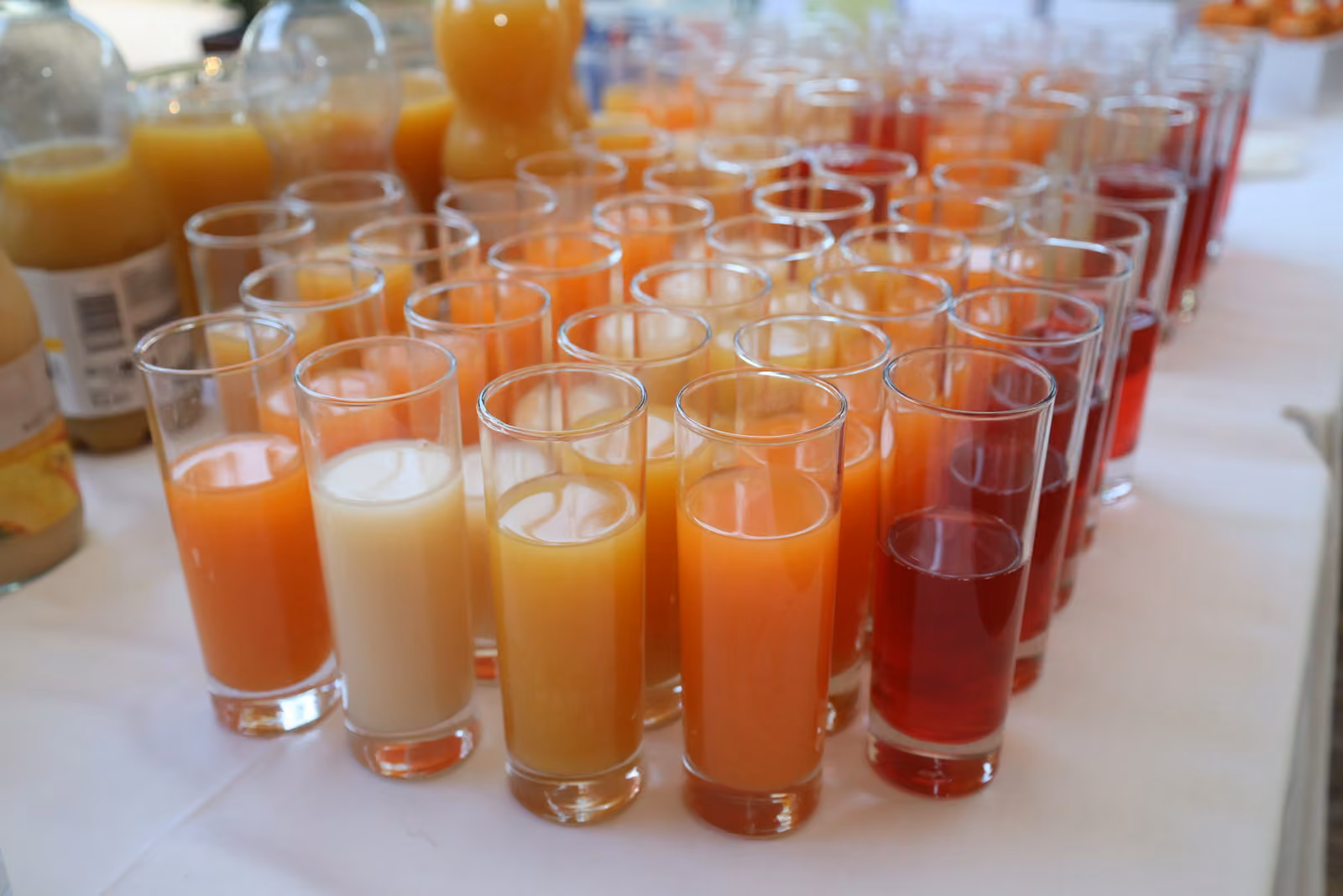 Verres de jus frais d'orange, d'ananas et de fruits rouges alignés pour le vin d'honneur