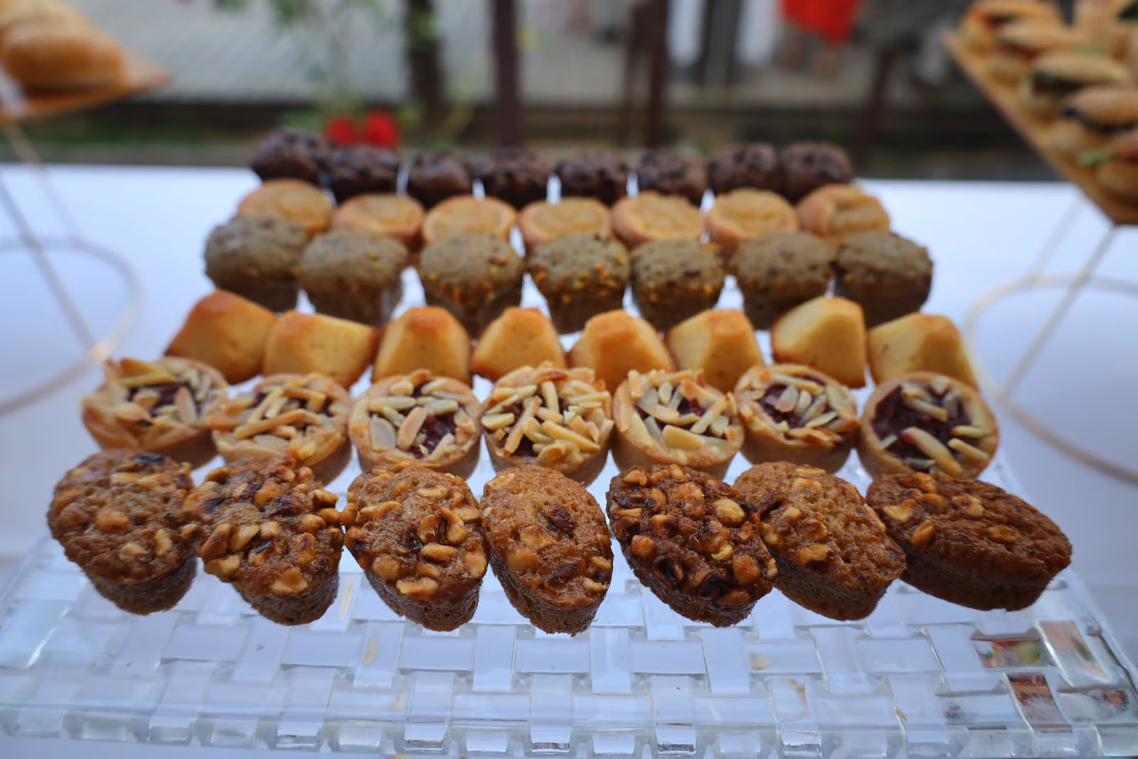 Mini-cakes, financiers aux pignons et tartelettes alignés sur un plateau en verre